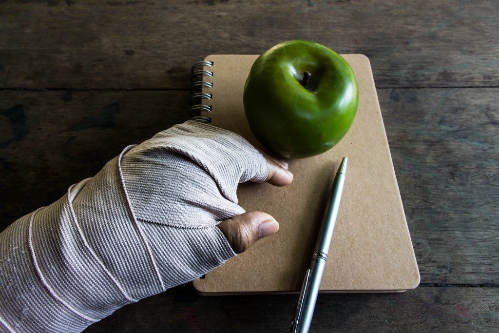 bandaged hand, apple, and notebook