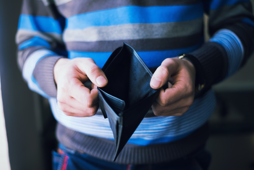 A person with empty wallet showing bankruptcy sign