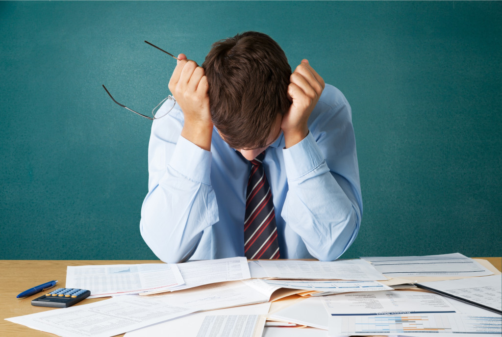 A stressed businessman on a desk with messy paperwork