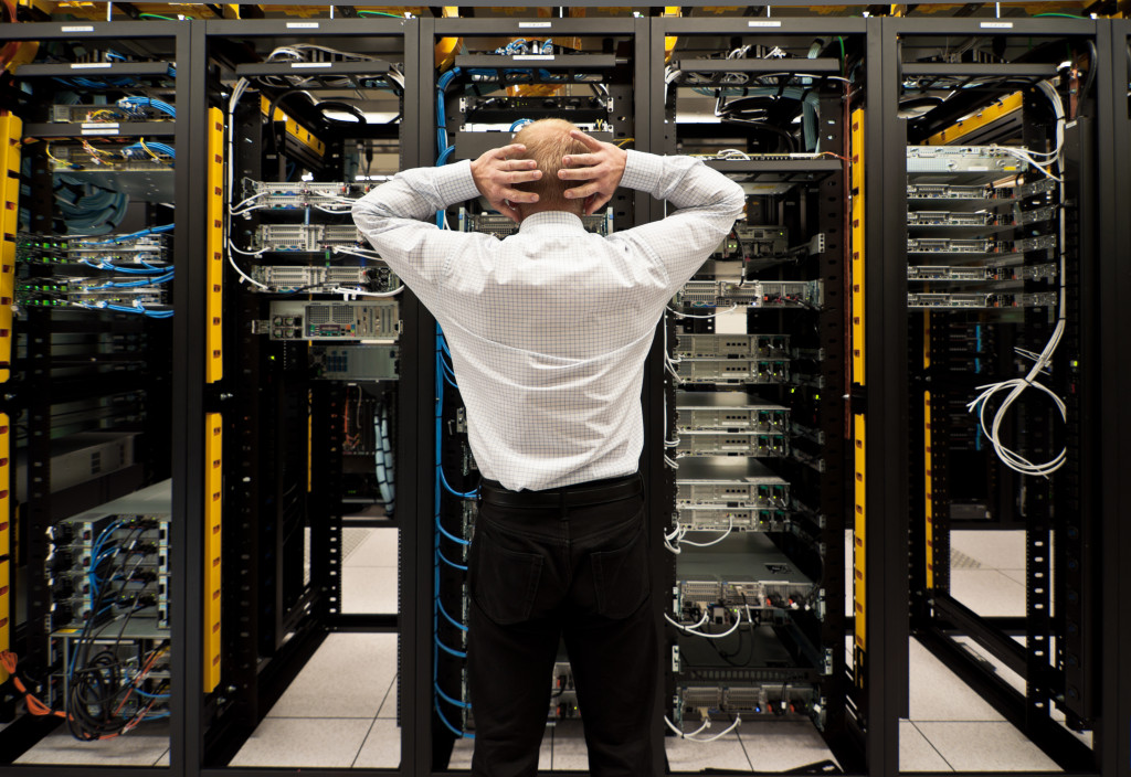 Puzzled employee looking at the servers of the data center of a business.