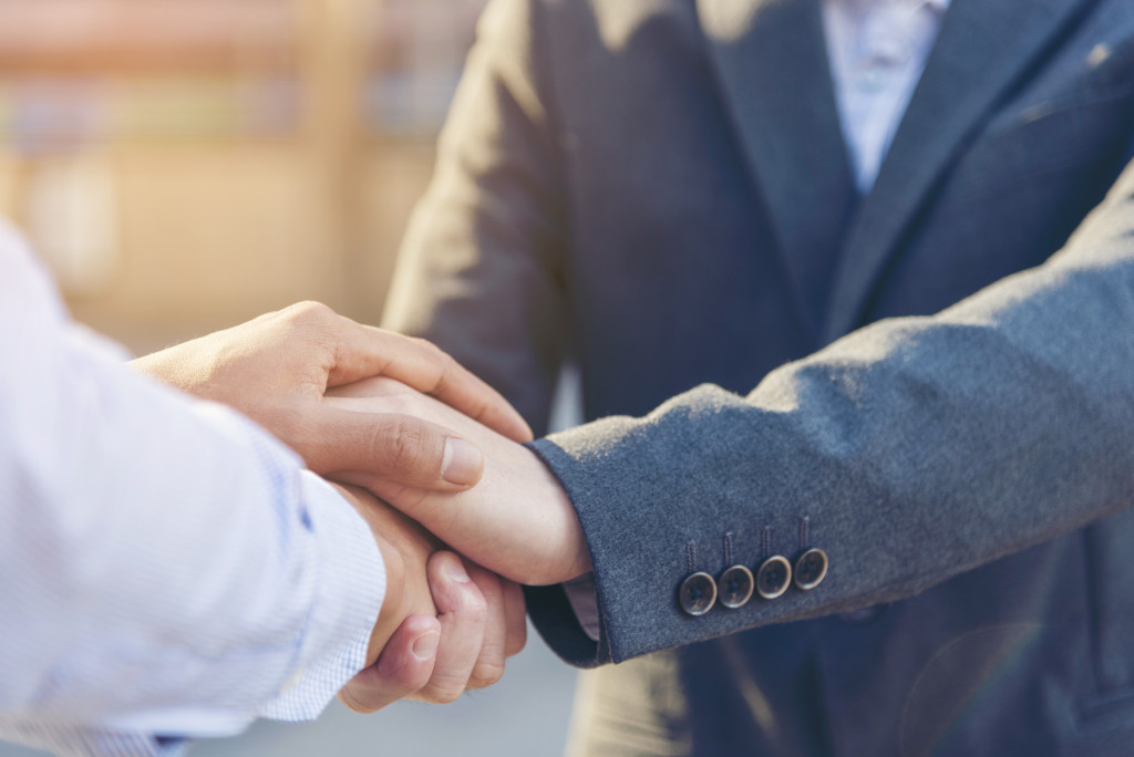 man in suit reassuring another man by clasping their hand